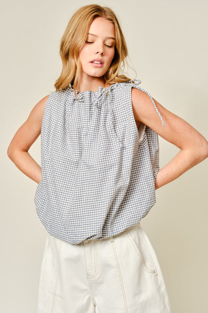 Woman wearing a sleeveless checkered top with a plain background