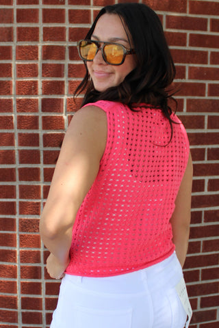 Bright pink sleeveless open knit sweater tank styled with white trousers for a summer outfit.