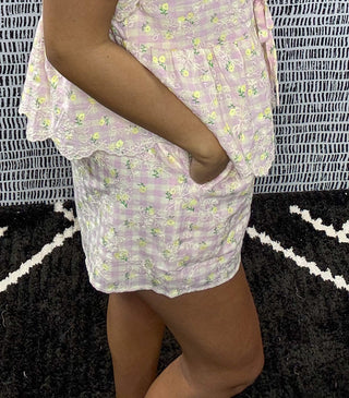 Side view of woman wearing pastel pink floral gingham two-piece summer set with tie front top and shorts, boutique outfit for women