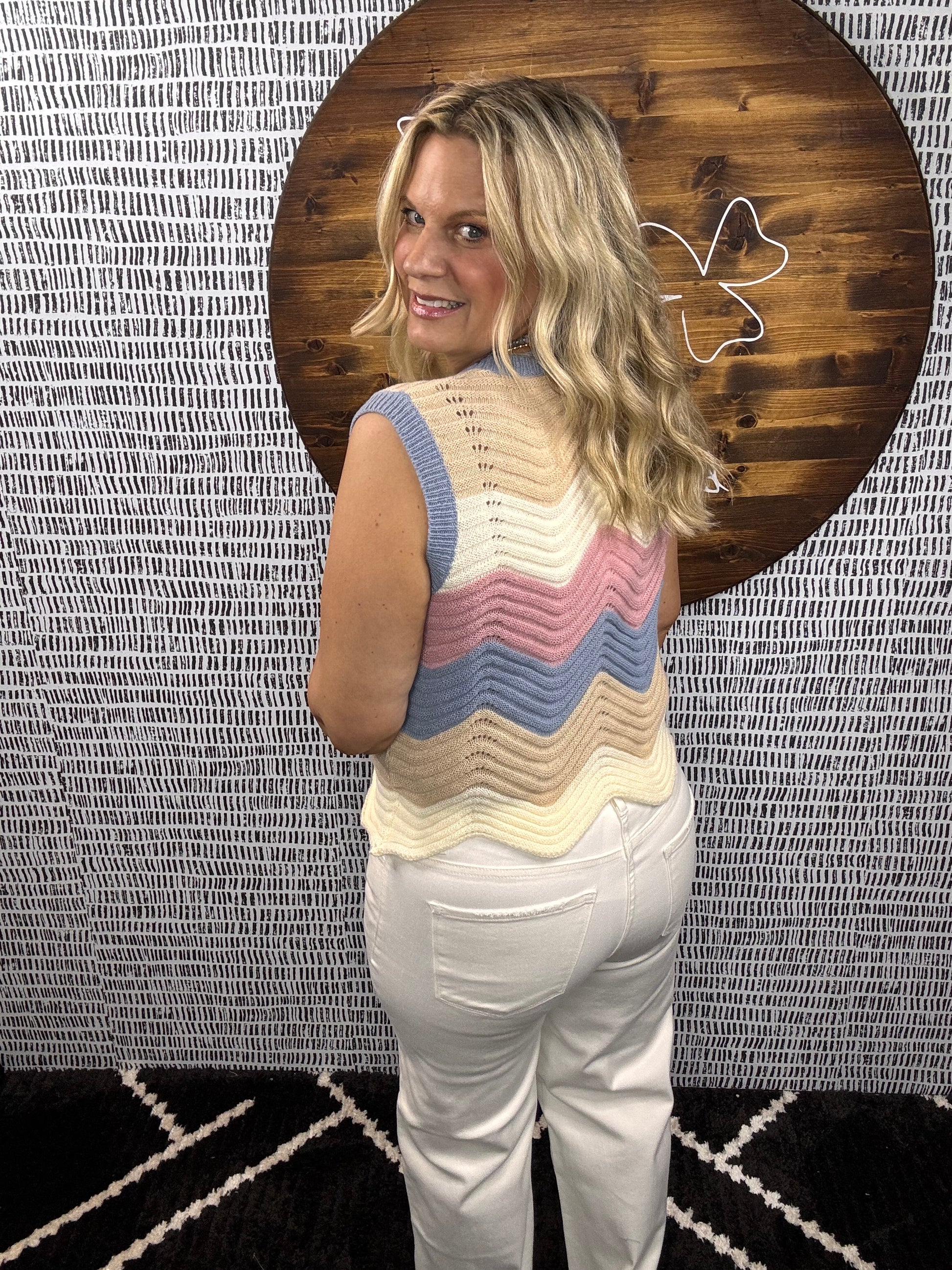 Back view of model wearing multicolor chevron knit sleeveless sweater top with pastel stripes – Erin Rose Boutique.