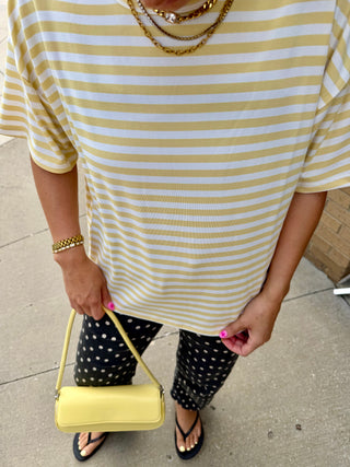 Woman wearing the Butter Yellow Lennon Striped Top paired with black polka dot pants, layered gold necklaces, and a yellow handbag.