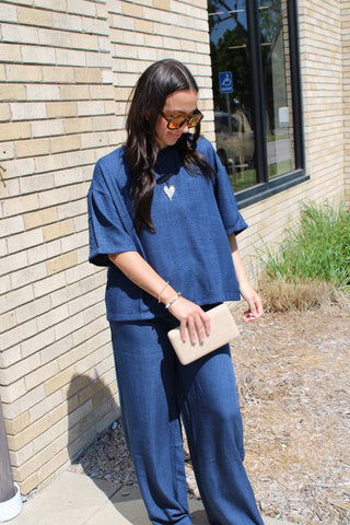 Woman wearing navy relaxed fit tie back top with lightweight flowy fabric and matching wide leg pants