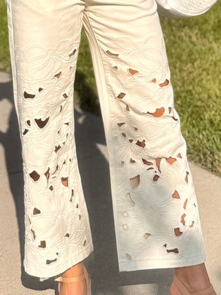cream denim wide leg pants with floral cutouts & embroidered design on legs of jeans