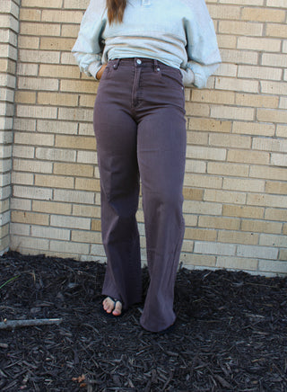 A person wearing dark brown flared jeans available at Erin Rose Boutique