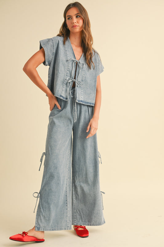 Woman wearing high-waisted wide leg denim pants with side bow tie details and relaxed fit.  Obsessed viral denim bottoms at Erin Rose Boutique.