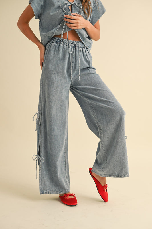Woman wearing high-waisted wide leg denim pants with side tie details and elastic waistband