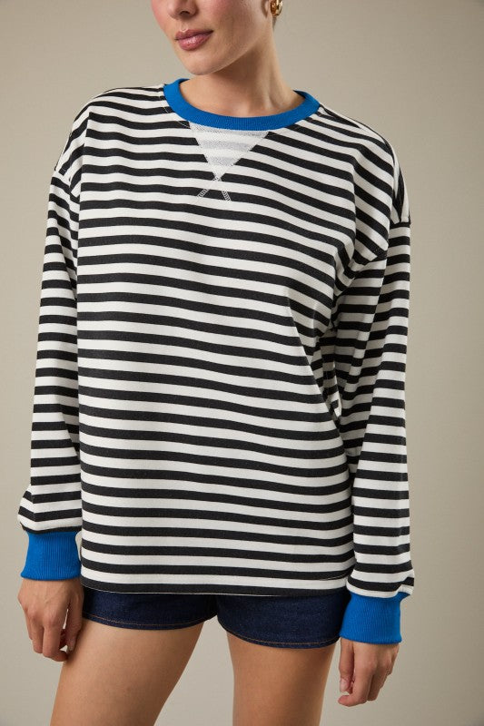 Person wearing a black and white striped long-sleeve shirt with blue cuffs and trim.
