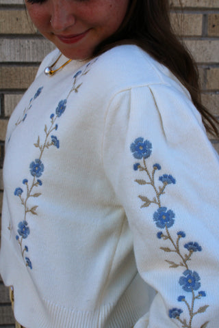 Ivory knit sweater with blue floral embroidery along the balloon sleeve