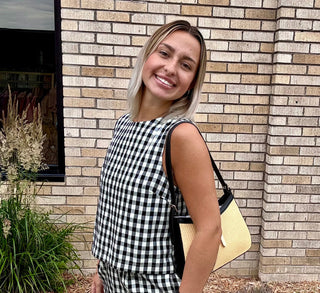 Woman wearing black and white gingham sleeveless top with matching shorts outside a boutique
