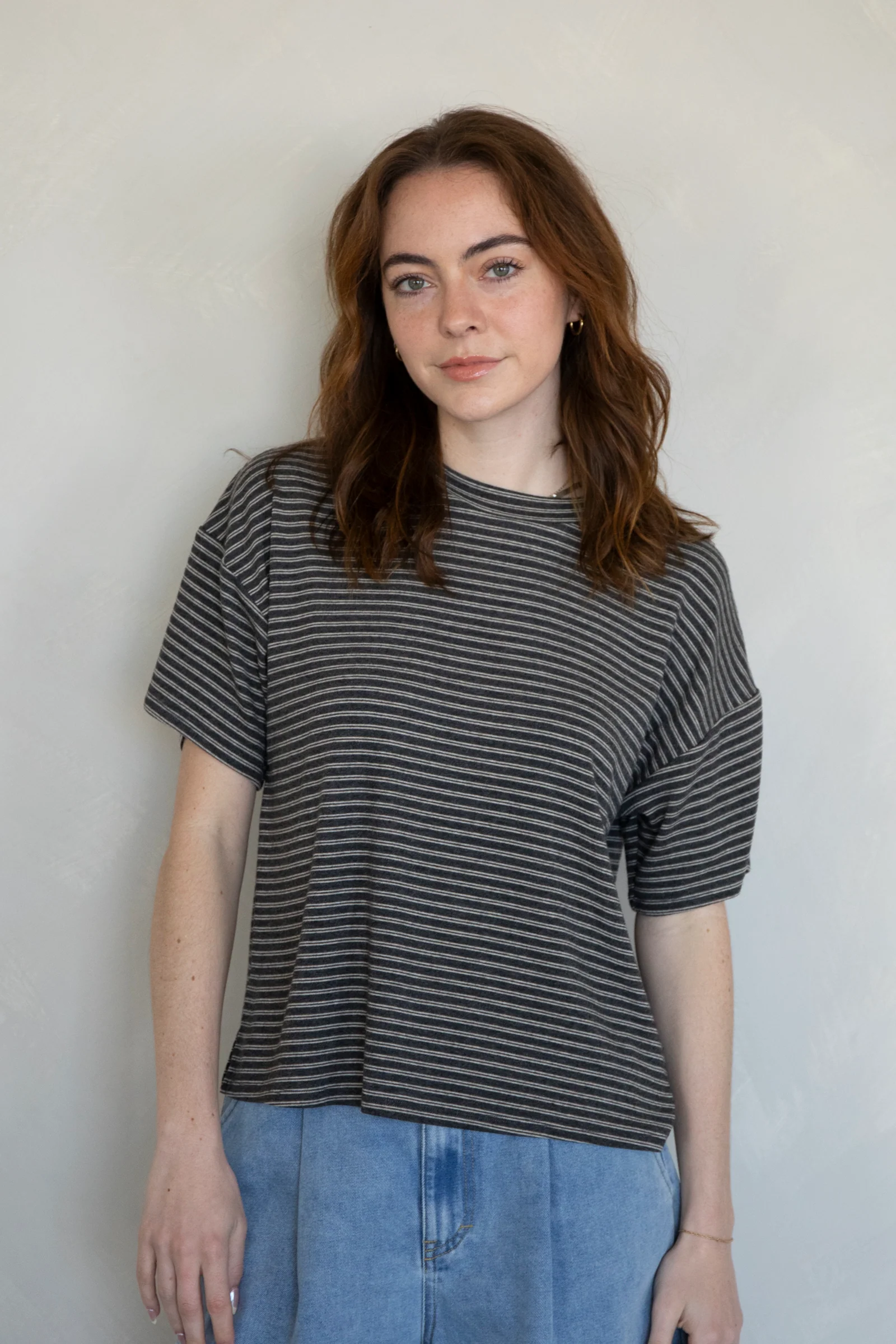 Woman wearing a black and gray striped shirt against a plain background