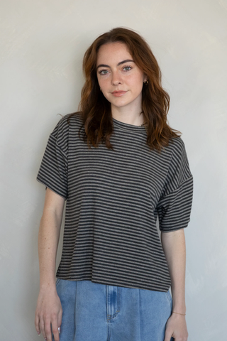 Woman wearing a black and gray striped shirt against a plain background