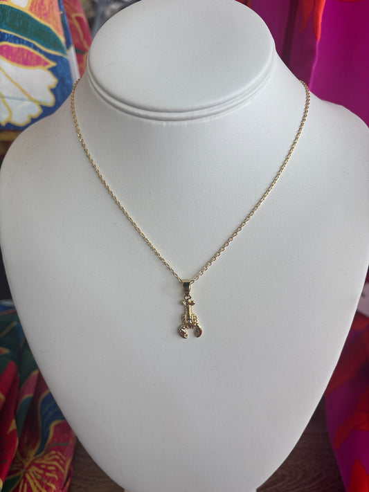 Dainty gold lobster charm necklace on display with fine chain and coastal-inspired pendant by Pink Kaitydid available at Erin Rose Boutique.