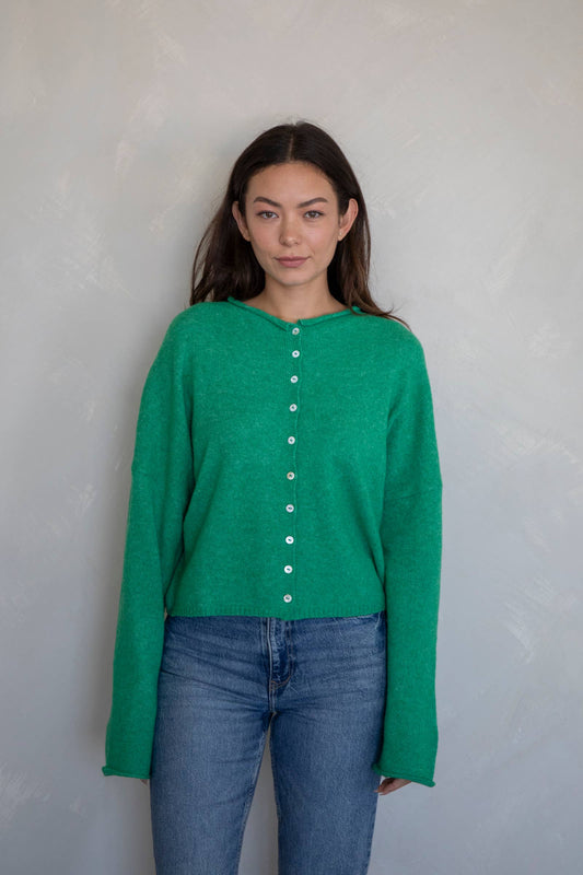 Woman wearing an emerald green button-down lightweight knit sweater cardigan with long sleeves and relaxed fit, perfect for spring layering

