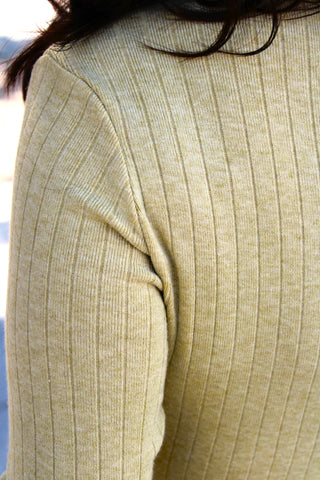 Close-up of Cozy Cottage Cardigan highlighting the ribbed knit fabric a  in a light green fig color, showing the shoulder and sleeve texture.