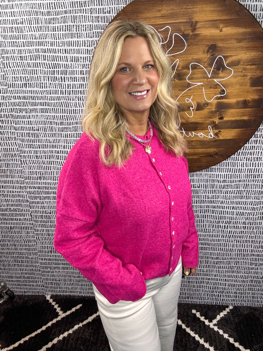 Model wearing hot pink button-down cardigan with pearl buttons, styled with white pants for a vibrant, cozy look – Erin Rose Boutique
