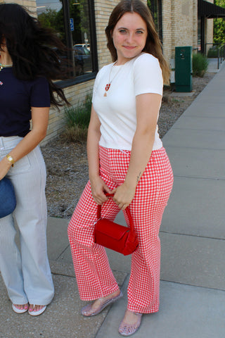 Woman styling red gingham straight leg jeans with white fitted tee and red handbag.