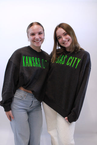 Two people wearing black hoodies with green text on a white background