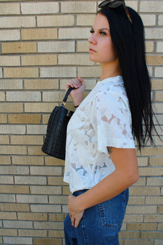 Side view of Lainey ivory floral lace short sleeve top styled with dark wash jeans