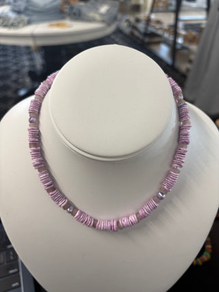Lavender puka shell necklace with mixed purple beads displayed on a white bust stand, trendy summer jewelry