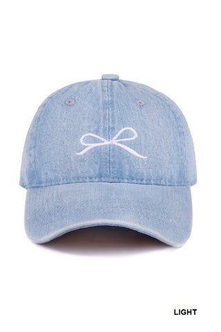 Light blue denim cap with a white bow embroidered on it.  Available at Erin Rose boutique.