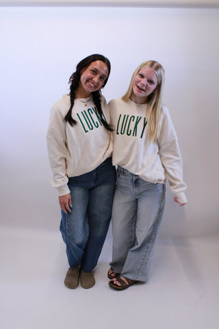 Two people wearing matching beige sweatshirts with text on a white background
