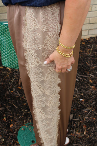 A close-up of a person wearing Mocha satin balloon pants with ivory lace side panel detail