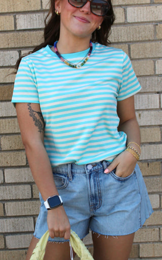 Person wearing a blue and white striped shirt and denim shorts available at Erin Rose Boutique