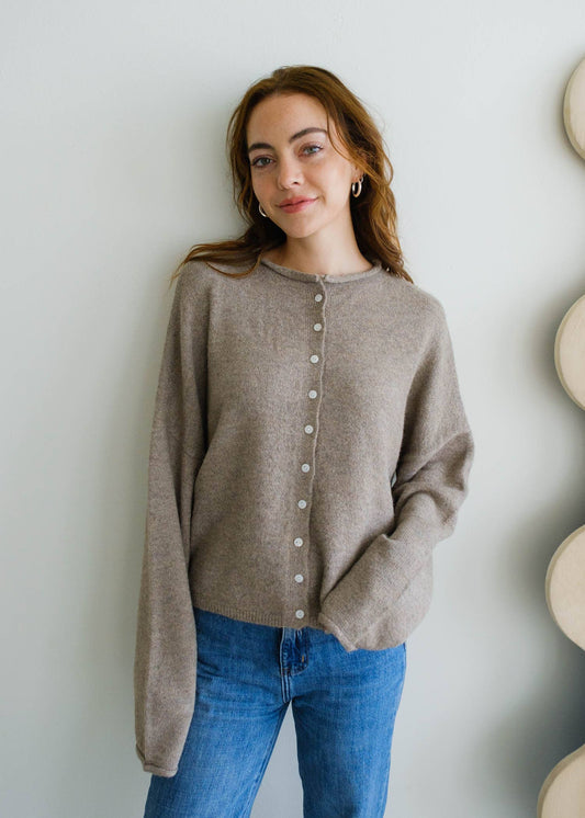 Woman wearing a lightweight mocha button-down Piper cardigan sweater styled with denim jeans, perfect for layering in any season