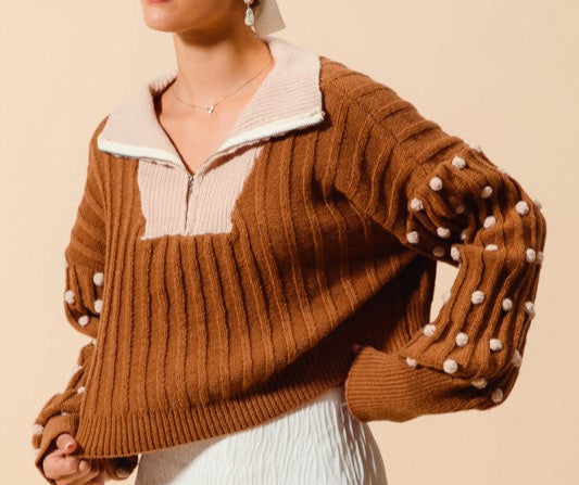 Woman wearing a mocha brown sweater with white polka dot puffs on sleeves  available at Erin Rose Boutique