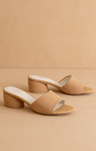 Pair of neutral block heel slide sandals with open toe and raffia-wrapped insole detail on a beige background.