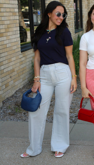 Woman wearing striped high rise wide leg jeans with navy graphic tee and woven handbag available at Erin Rose Boutique