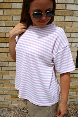 Woman wearing Lennon Stripe Tee in orchid pink and white stripes with an oversized relaxed fit.