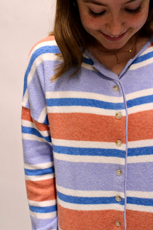 Close-up of a pastel striped button front cardigan in periwinkle, coral, blue, and cream tones.