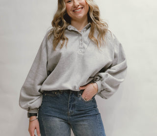 Person wearing a light gray sweater and blue jeans on a plain background