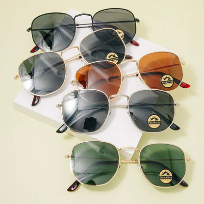 A variety of polarized retro square sunglasses with mixed metal frames in gold and black, featuring tinted lenses in black, brown, and green, displayed on a soft cream background  now at Erin Rose Boutique.