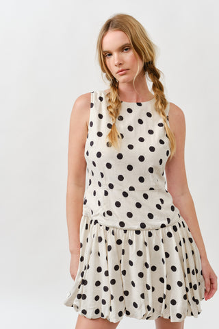Woman wearing sleeveless polka dot dress with bubble hem