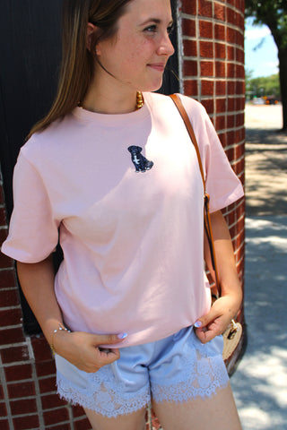 Model wearing the Pup Club Embroidered Tee in blush pink sorbet with an embroidered puppy detail, paired with blue lace satin shorts for an effortlessly cute everyday look.