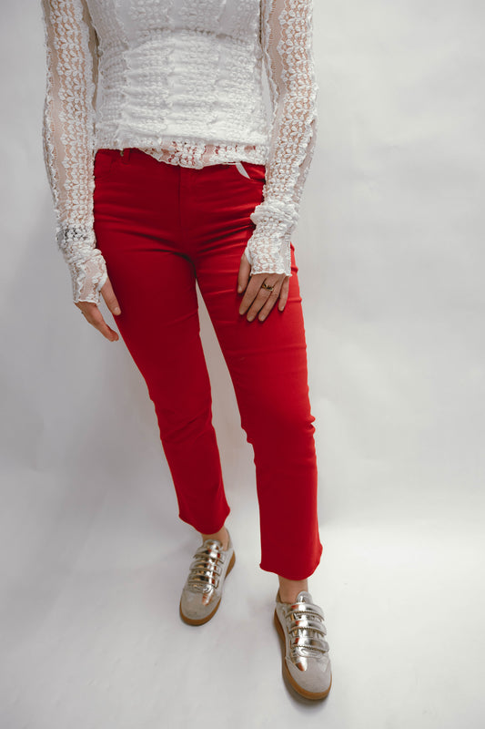 Person wearing a white lace top and red denim  pants on a plain background available at Erin Rose Boutique