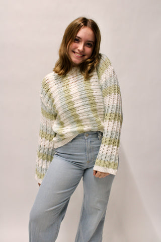 Cream and sage striped open knit sweater with relaxed fit styled with light blue striped pants.