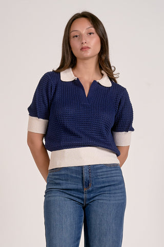 Woman wearing a blue and white polo shirt with blue jeans on a plain background
