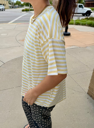 Model styling the Butter Yellow Lennon Striped Top with black polka dot pants and a coordinating butter yellow purse.