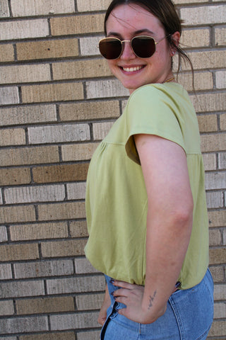 Side view of Tilly Bubble Hem Top in avocado green featuring a relaxed fit, gathered yoke detail, and bubble hem design available at Erin Rose Boutique