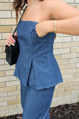 A woman wearing a blue pinstripe strapless top and matching pants.