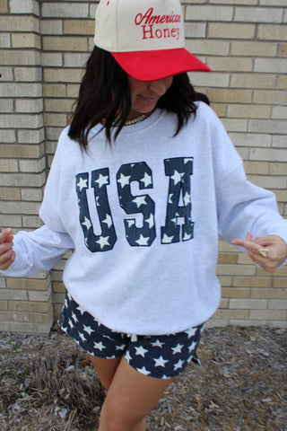 Heather gray oversized USA sweatshirt with navy star graphic lettering paired with patriotic star print shorts