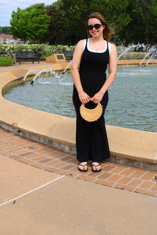 Woman wearing black ribbed maxi tank dress with contrast trim detail and relaxed summer styling.