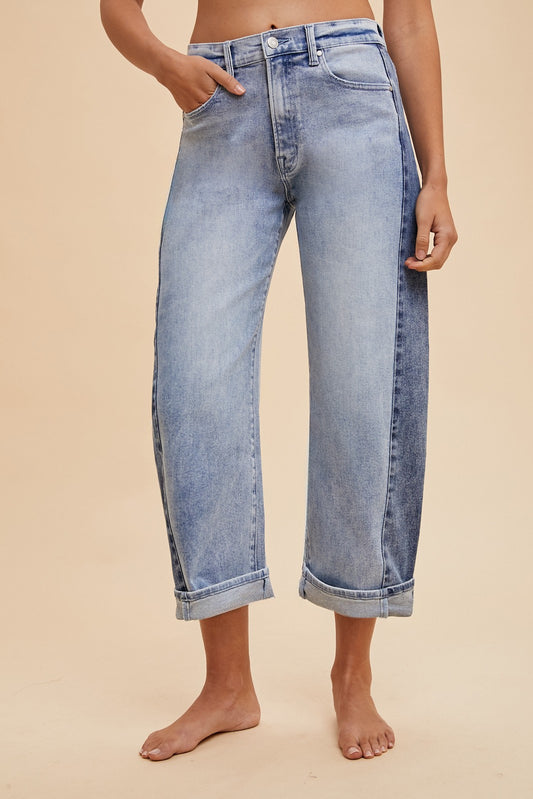 Model wearing light wash two-tone barrel leg jeans with rolled cuffs and high waist