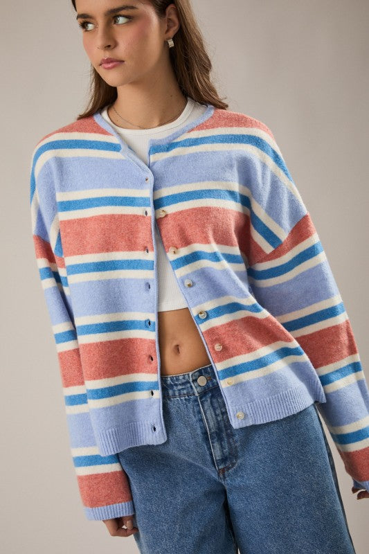 woman wearing a colorful blue and coral striped cardigan with a neutral background available at Erin Rose Boutique