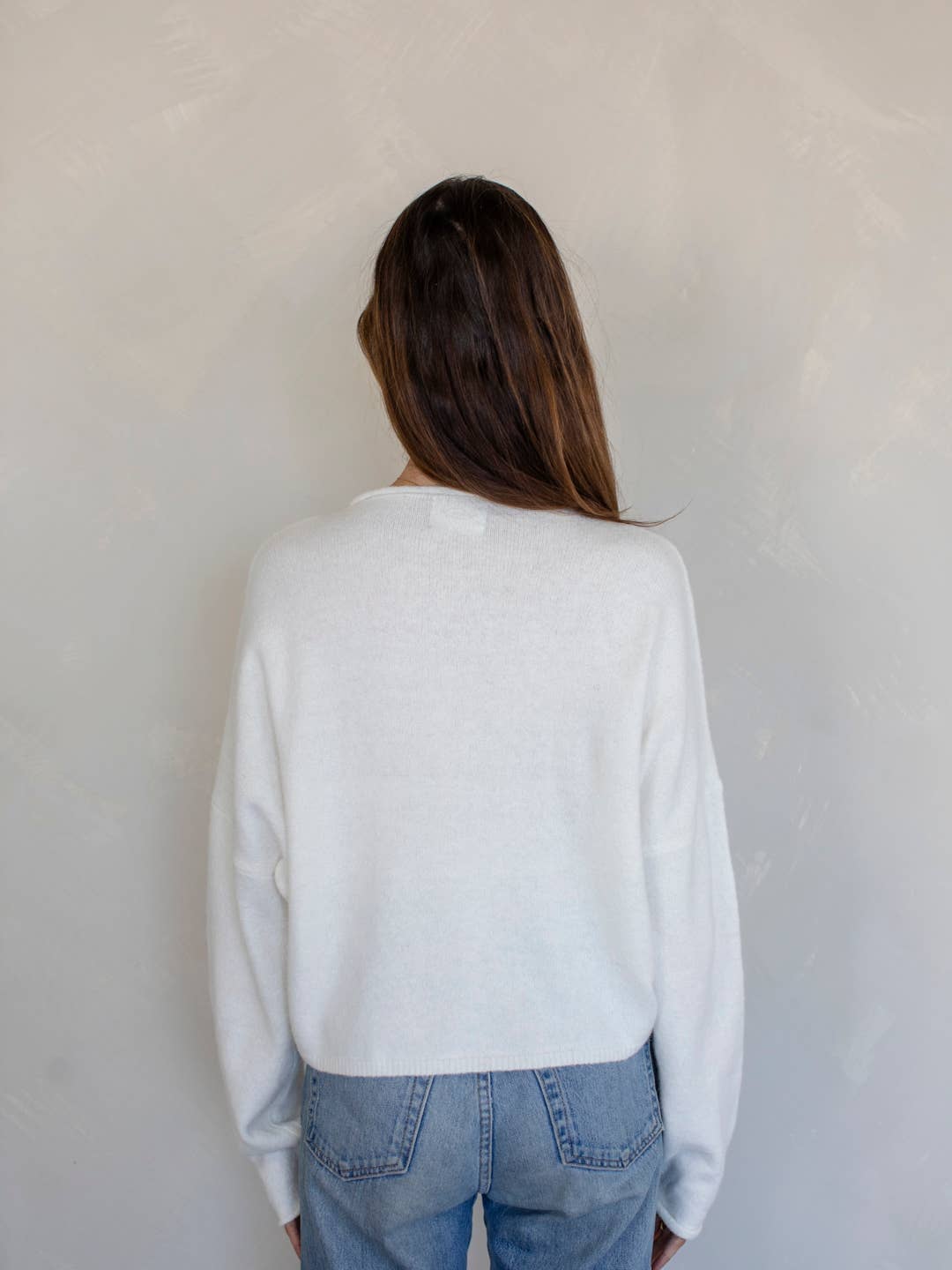 Back view of model wearing white knit button-down cardigan with relaxed fit and high-rise denim – Erin Rose Boutique