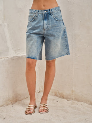 Woman wearing light wash wide-leg Bermuda denim shorts with a vintage-inspired fit.
